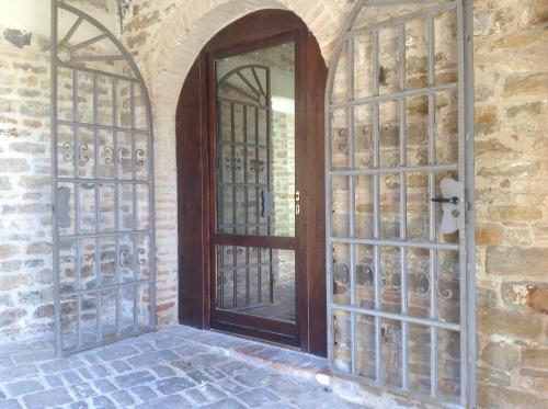 a wooden door in a brick wall with a window at Le Copertelle Bed & Breakfast in Serra San Quirico