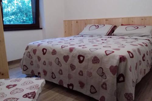 Una cama con una manta con corazones. en Casa vacanze Insieme en Baselga di Pinè