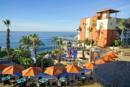 a resort with tables and umbrellas and the ocean at Hyatt Vacation Club at Sirena del Mar in Cabo San Lucas