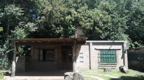 a small brick building with a green door and trees at Cuatro Estaciones in General Rodríguez