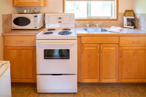 a kitchen with a white stove and a microwave at Rocky Mountain Ski Lodge in Canmore