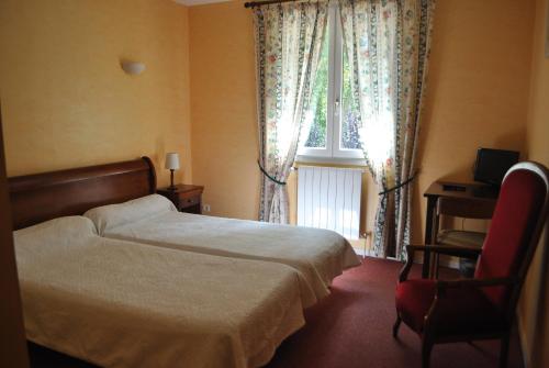 a bedroom with a bed and a window and a chair at Hôtel Auberge de La Nauze in Sagelat