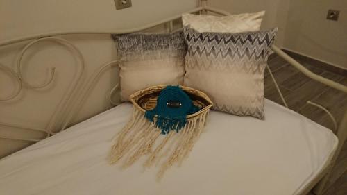 a white bed with two pillows and a basket on it at Stone house with seaview in Nea Potidaea