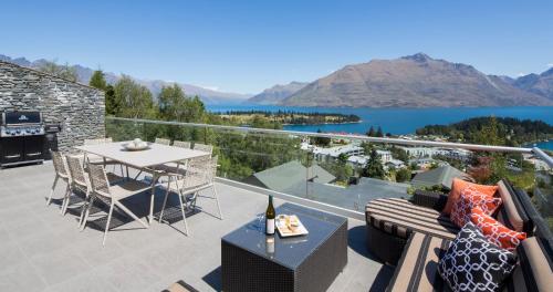 a balcony with a table and a view of a lake at Papillon, a Relax it's Done luxury holiday home in Queenstown