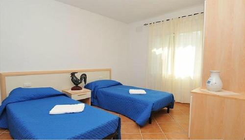 1 dormitorio con 2 camas azules y ventana en Gallo Spot en San Teodoro