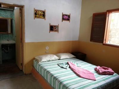 a bedroom with a bed with two pink towels on it at Hostal Nova Colonial in Puerto Colombia