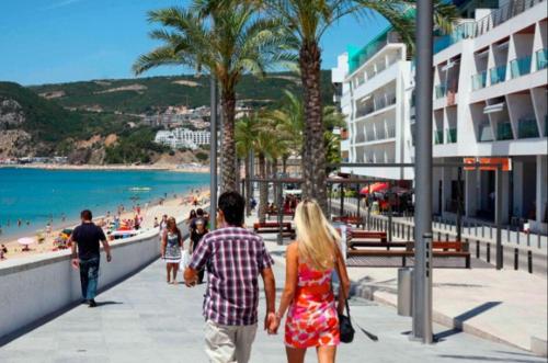 a man and woman walking down a sidewalk near the beach at Sesimbra Beach Fonte House in Sesimbra