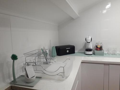 a white kitchen with a dish rack and a sink at Sesimbra Beach Fonte House in Sesimbra
