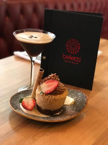a dessert with strawberries on a plate next to a drink at Dandenong Central Apartments Official in Dandenong