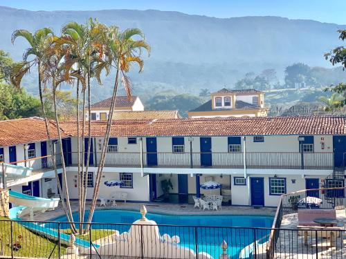 un complexe avec une piscine et des palmiers dans l'établissement Hotel Ponta do Morro, à Tiradentes