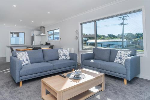 a living room with two blue couches and a coffee table at Kaka Point Views Apartment 1 in Kaka Point