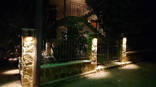 a fence with lights in front of a building at night at Stone house with seaview in Nea Potidaea