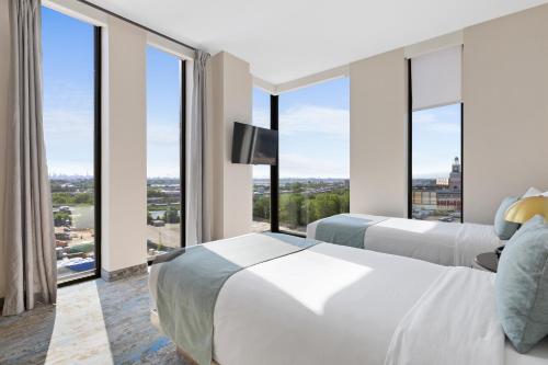 two beds in a hotel room with large windows at The Parc Hotel in Queens