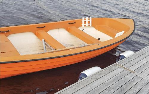 an orange boat sitting on the water next to a dock at Lovely Home In Värnamo With Wifi in Värnamo