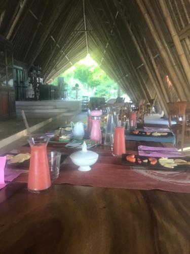 a table with pink vases and plates of food at Eco dive resort Alycastre in Maumere