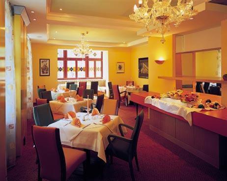 um restaurante com mesas e cadeiras e uma sala de jantar em Hotel am Kurpark em Schönebeck