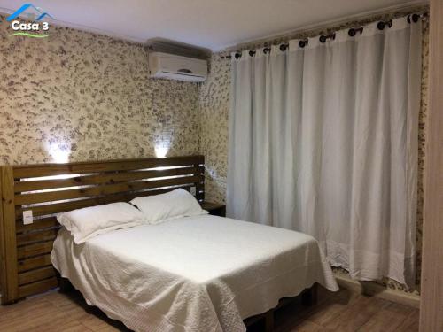 a bedroom with a bed with white sheets and curtains at Residencial Dona Preta in Florianópolis