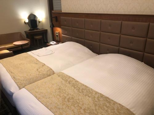a hotel room with a large bed with white sheets at Kobe Luminous Hotel Sannomiya in Kobe