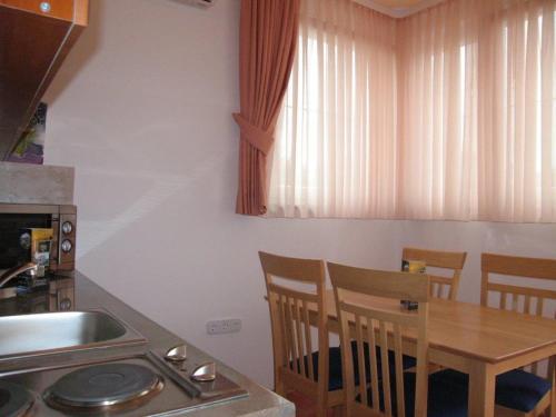 a kitchen with a wooden table with chairs and a sink at Apartments Stengl in Rab