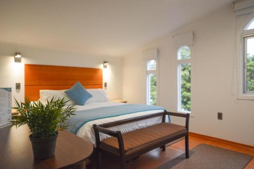 a bedroom with a bed and a bench and windows at Kai Bed and Breakfast in Algarrobo