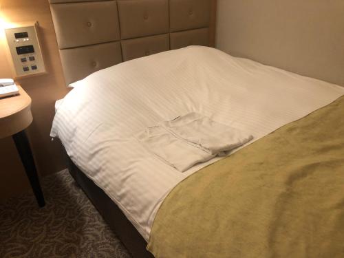 a bed with a white shirt sitting on it at Kobe Luminous Hotel Sannomiya in Kobe