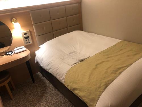 a bedroom with a bed and a desk with a lamp at Kobe Luminous Hotel Sannomiya in Kobe