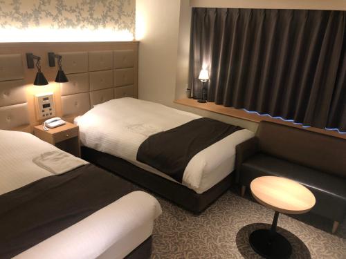 a hotel room with two beds and a couch at Kobe Luminous Hotel Sannomiya in Kobe