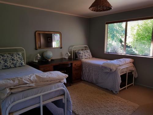 a bedroom with two beds and a desk and a mirror at Haurata High Country Retreat/walks in Gisborne