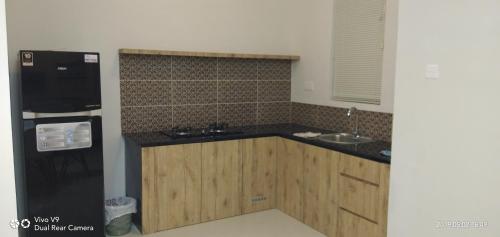 a kitchen with wooden cabinets and a black refrigerator at SleepRest @ The Home Shoutlink in Nagoya