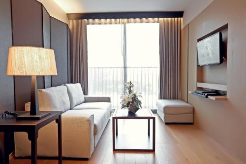 a living room with a couch and a table at Arcadia Suites Bangkok in Bangkok