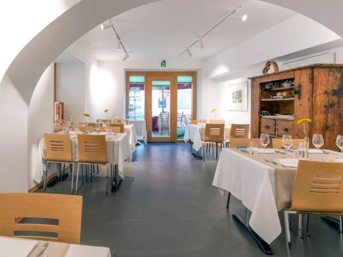 ein Restaurant mit weißen Tischen und Stühlen sowie einem Torbogen in der Unterkunft Hotel Centrale, Typically Swiss in Poschiavo