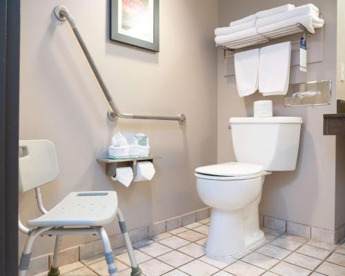 a bathroom with a toilet and a chair and towels at Pocaterra Inn & Waterslide in Canmore