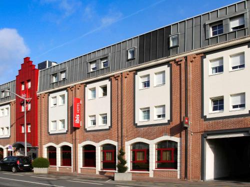 a red and white building on the side of a street at ibis Lille Lomme Centre in Lomme