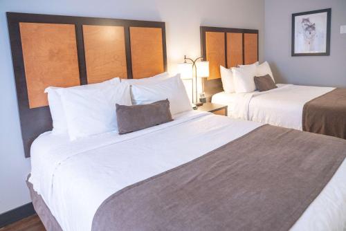 a hotel room with two beds with white sheets at Pocaterra Inn & Waterslide in Canmore