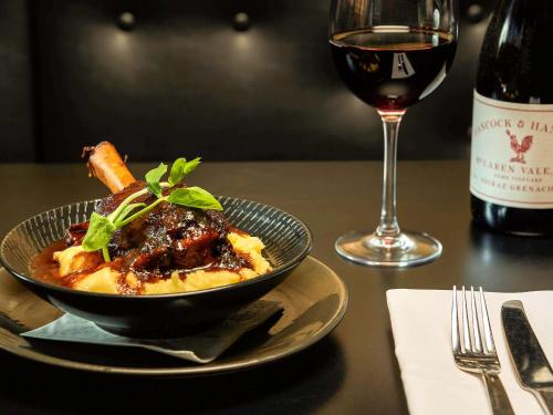 a bowl of food on a table with a glass of wine at ibis Adelaide in Adelaide