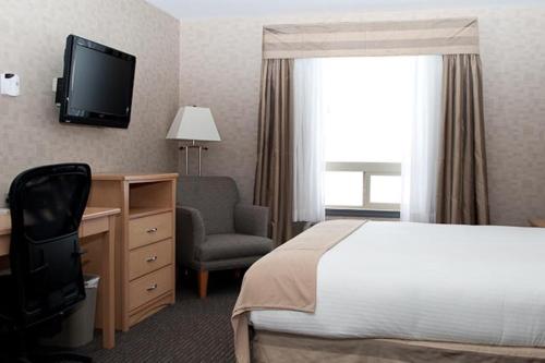 a hotel room with a bed and a chair and a television at Paradise Inn and Suites in Valleyview