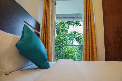 een bed met een groen kussen en een raam bij Lamond Holidays Munnar in Munnar