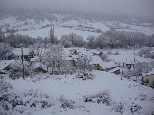 a village covered in snow with trees and houses at O´Porron in Sabiñánigo