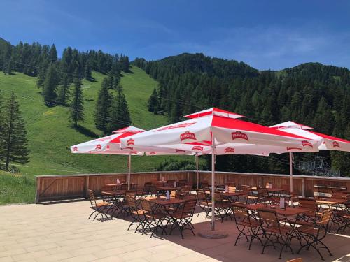 a patio with tables and chairs and umbrellas at JUFA Hotel Malbun in Malbun