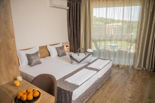 a hotel room with a bed and a table with oranges on it at Allure Beach Resort Aparthotel in Primorsko