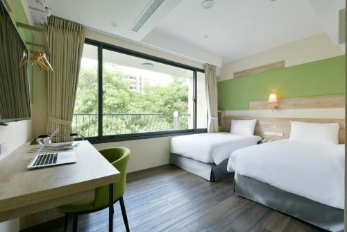 a hotel room with two beds and a desk at Hotel Kuei in Taichung