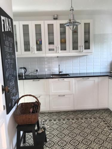 a kitchen with white cabinets and a basket on a stool at Trajadinha - Swedish House in Caminha