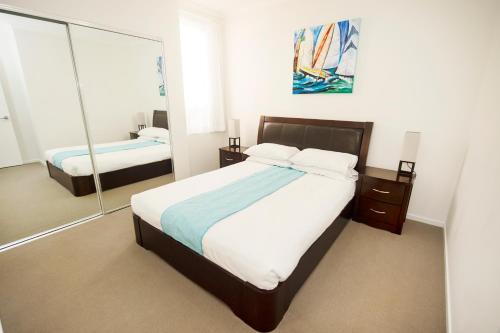a bedroom with a large bed and a mirror at Curtis Central Apartments Official in Gladstone