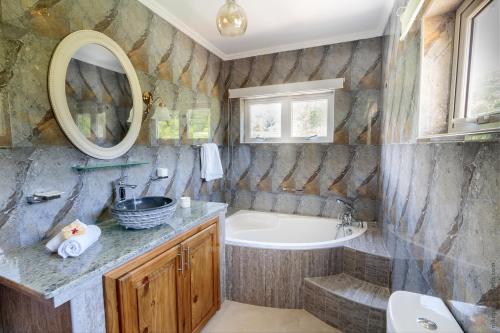 ein Badezimmer mit einer Badewanne, einem Waschbecken, einer Badewanne und einem Spiegel in der Unterkunft Flora's Self Catering Apartments in Victoria