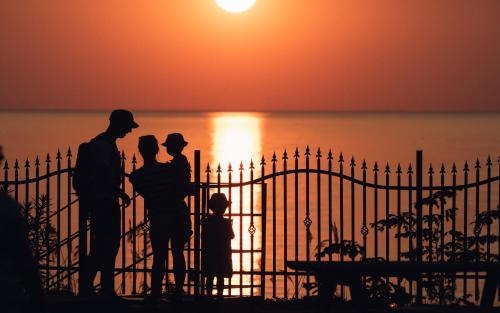 a family standing in front of a fence at sunset at Hotel Wodnik Twój Hotel z widokiem na morze in Ustronie Morskie