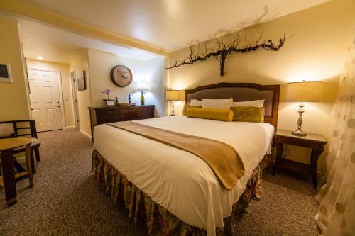 a bedroom with a large bed and a clock on the wall at The Vendange Carmel Inn & Suites in Carmel