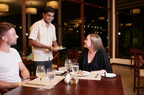 a group of people sitting around a table in a restaurant at The Calm Resort & Spa in Pasikuda