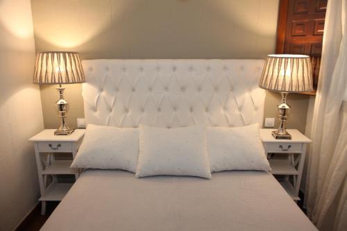 1 dormitorio con 1 cama blanca y 2 lámparas en Apartamento San Juan, en Cuenca