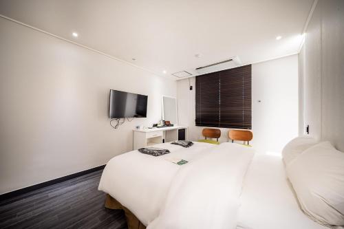 平澤的住宿－卡博酒店，白色的客房配有两张床和电视。