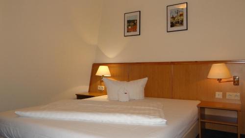 a bedroom with a white bed with two lamps at Hotel "Zur Post" in Spremberg